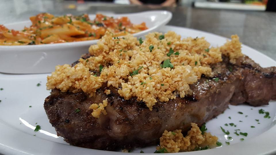 Steak with crumb topping served with pasta