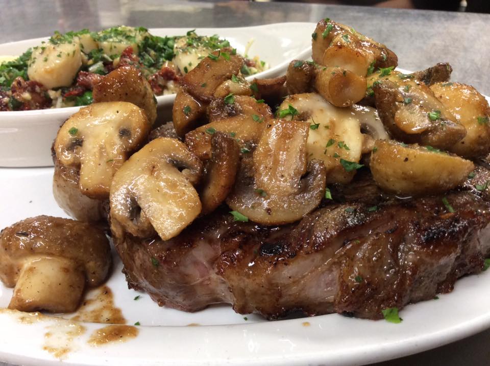 Grilled steak topped with sautéed mushrooms